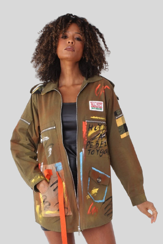 Model wearing army green graffiti print utility jacket with bold patches and graffiti inspired details — For Her NYC