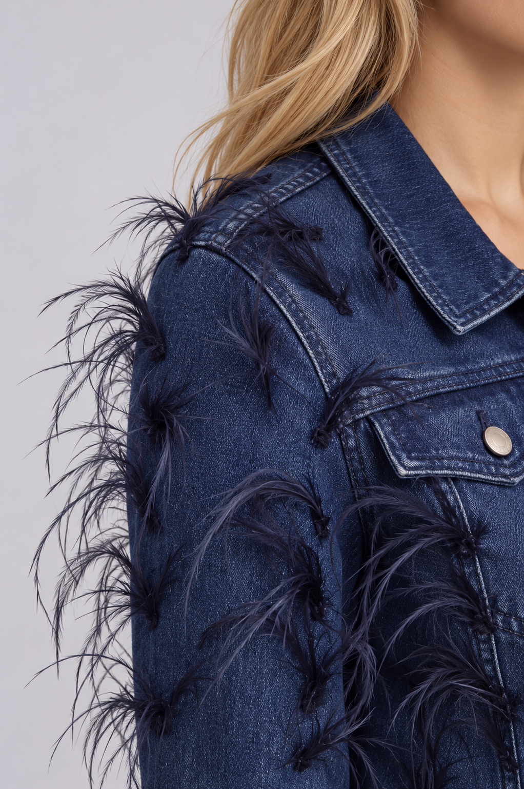 Shoulder close-up of a model wearing the dark-wash For Her NYC Feather Trim Denim Jacket - 82303, highlighting the wispy feather embellishments
