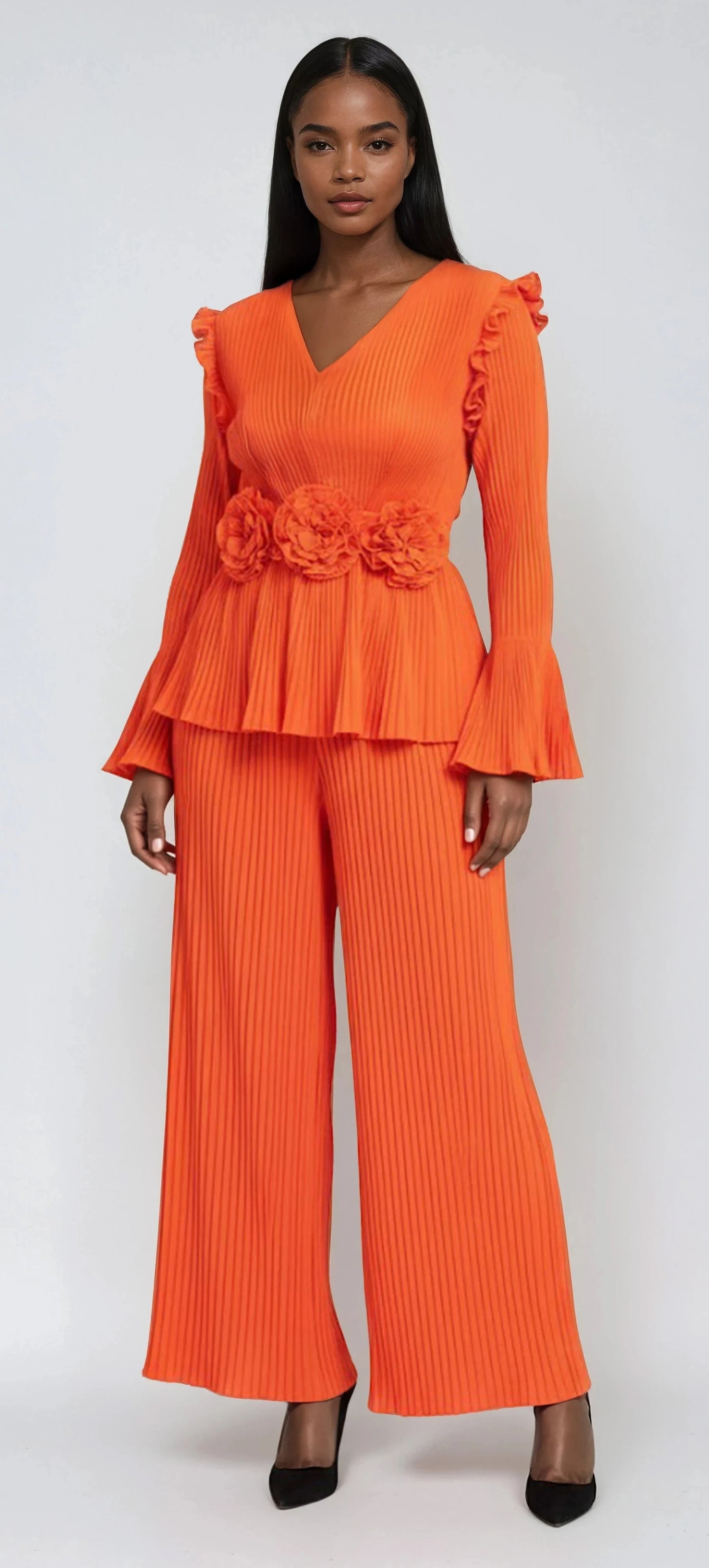 Model wearing orange pleated peplum pant set with floral waist detail and wide-leg pants by For Her NYC.