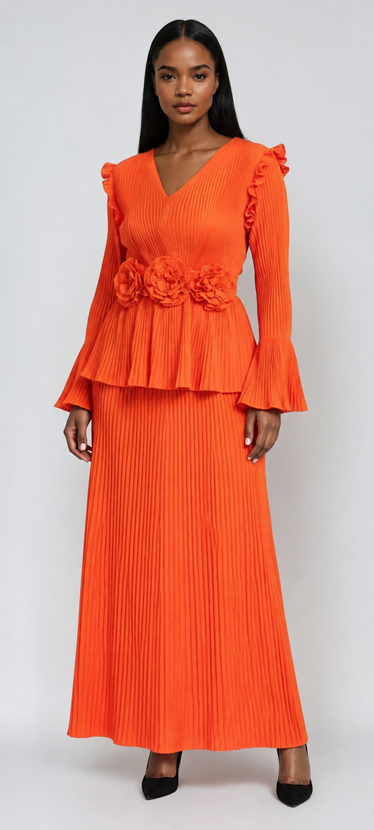 Model wearing orange pleated peplum skirt set with floral waist detail and wide-leg pants by For Her NYC.