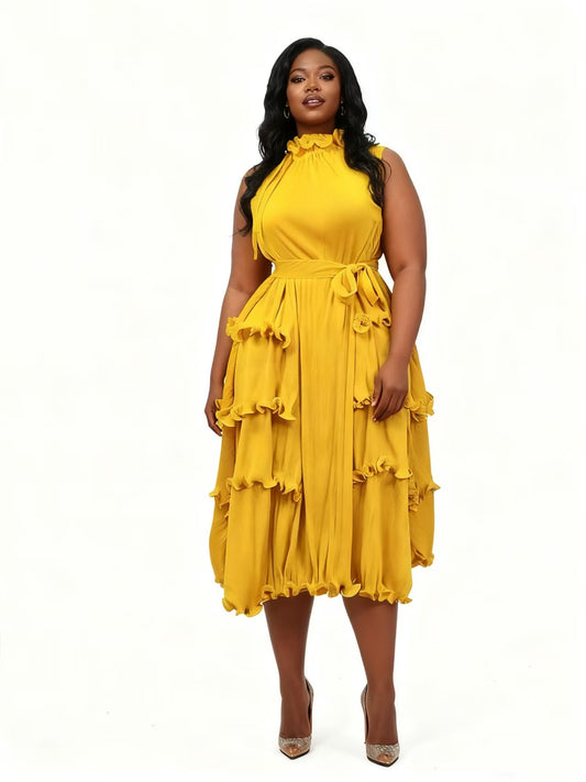 Front view of model wearing a yellow tiered midi dress with ruffle details and high neckline, For Her NYC