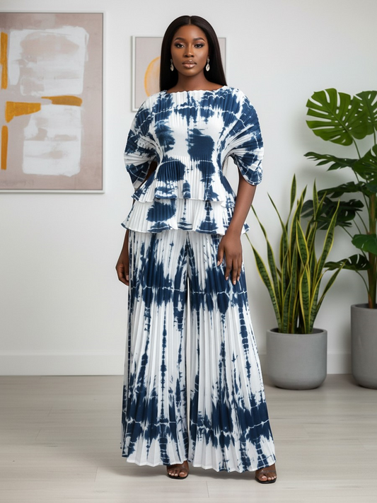 Front view of model wearing white and navy pleated tie-dye peplum top with wide-leg pants, For Her NYC