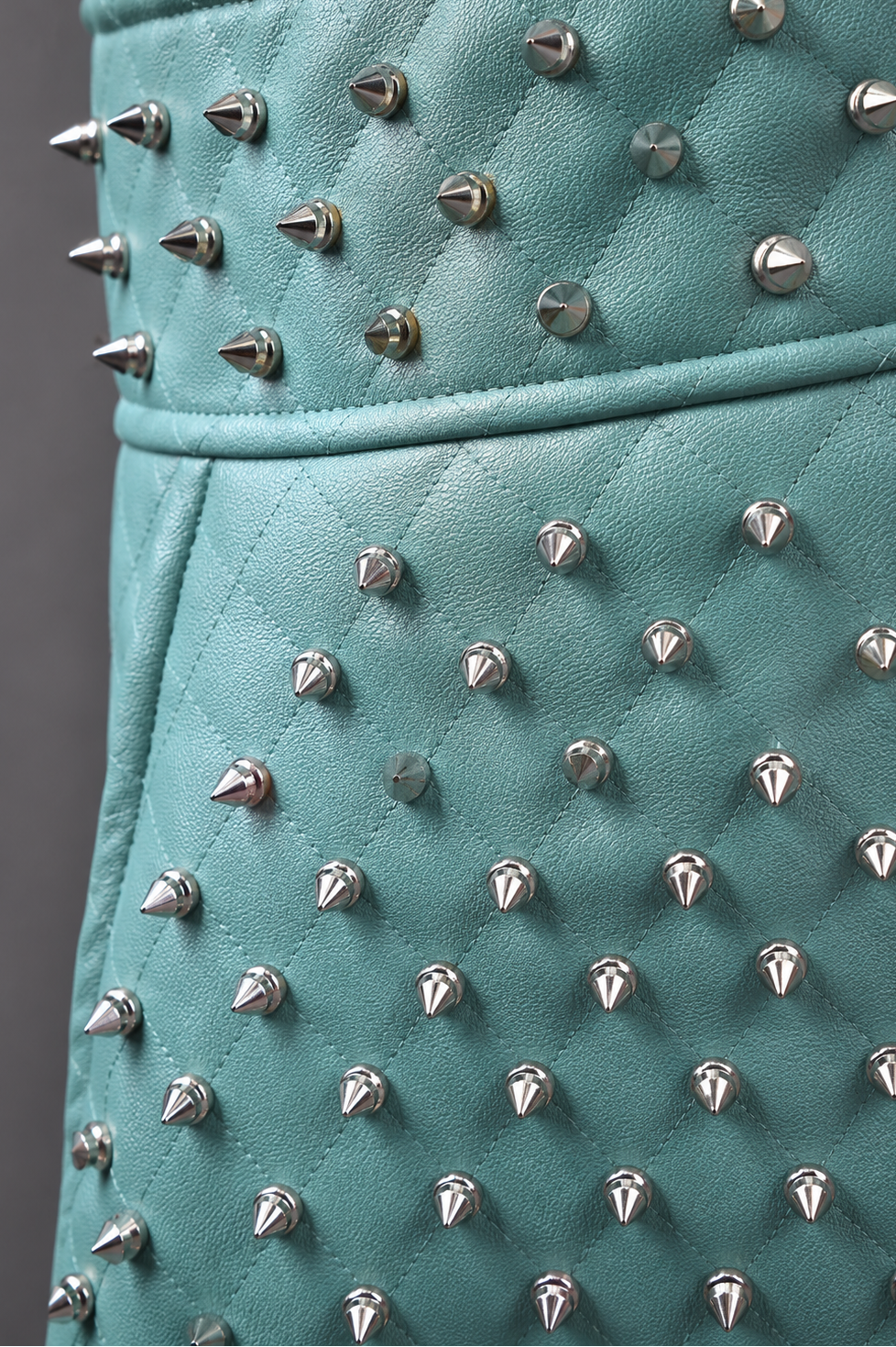 Model wearing pleather quilted flared skirt with studs in turquoise, front-facing hero pose highlighting flared silhouette, quilted texture, and statement stud detailing by For Her NYC