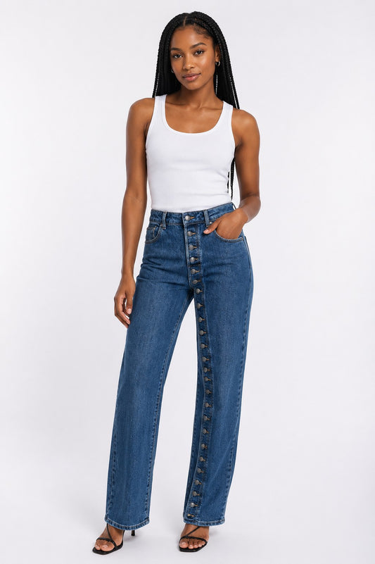 Model wearing the Side Button Detail Straight-Leg Denim Jeans in a medium wash featuring an off-center button front closure, a high-rise waist, and a straight-leg silhouette paired with a white tank top. For Her NYC.