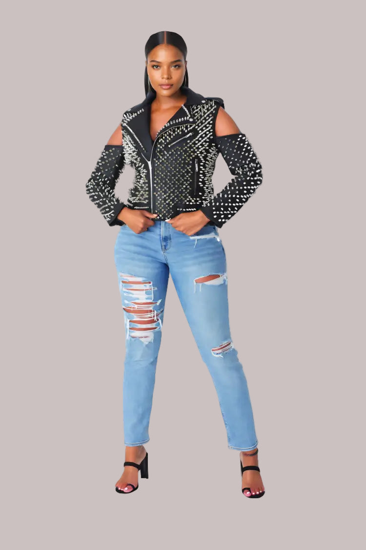Black studded pleather moto jacket with open shoulder cutouts shown from the front, styled with distressed skinny jeans and heels for an edgy look by For Her NYC