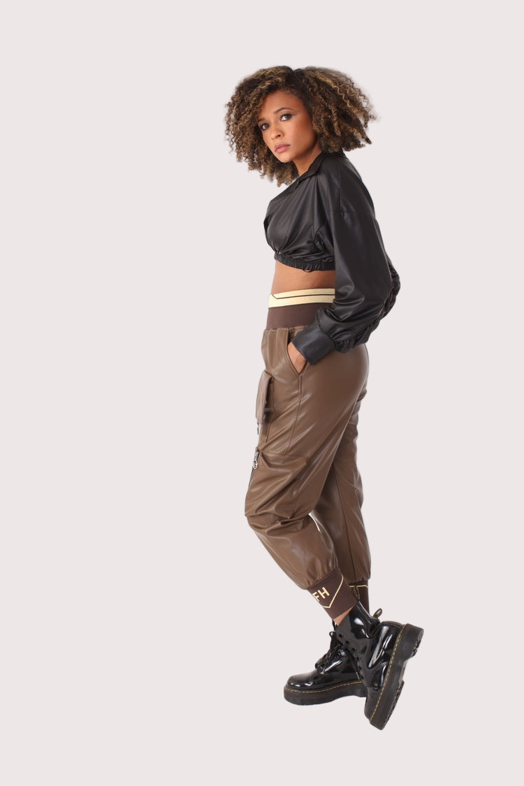 Angled pose of model wearing brown vegan leather cargo joggers with zipper accents and relaxed fit, bold edgy pants style, For Her NYC