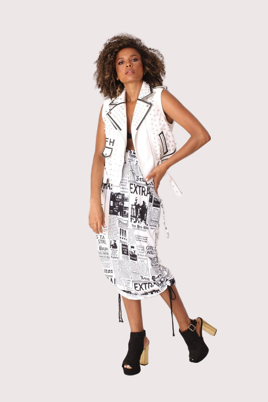 Model wearing a newsprint woven midi skirt in a front walking pose, showcasing the ruched waist and slim midi silhouette, For Her NYC