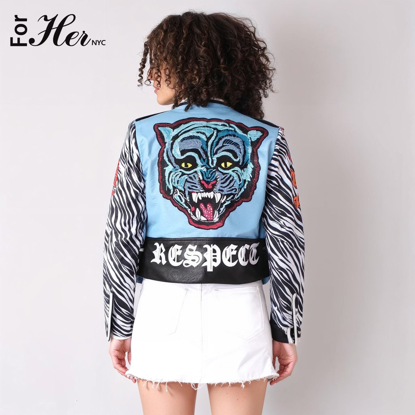 Zebra-print faux leather moto jacket showing back view with embroidered tiger and graffiti-inspired text, For Her NYC