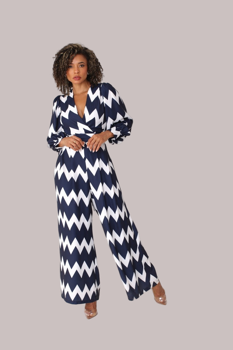 Model wearing navy and white chevron wide-leg jumpsuit with puff sleeves standing front-facing by For Her NYC