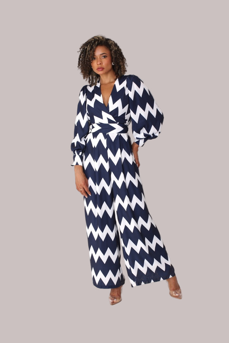 Model wearing navy and white chevron wide-leg jumpsuit with puff sleeves standing front-facing by For Her NYC