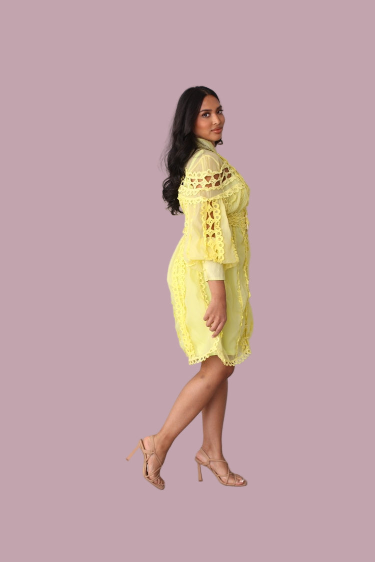 Model walking in yellow lace trim dress with feminine silhouette.