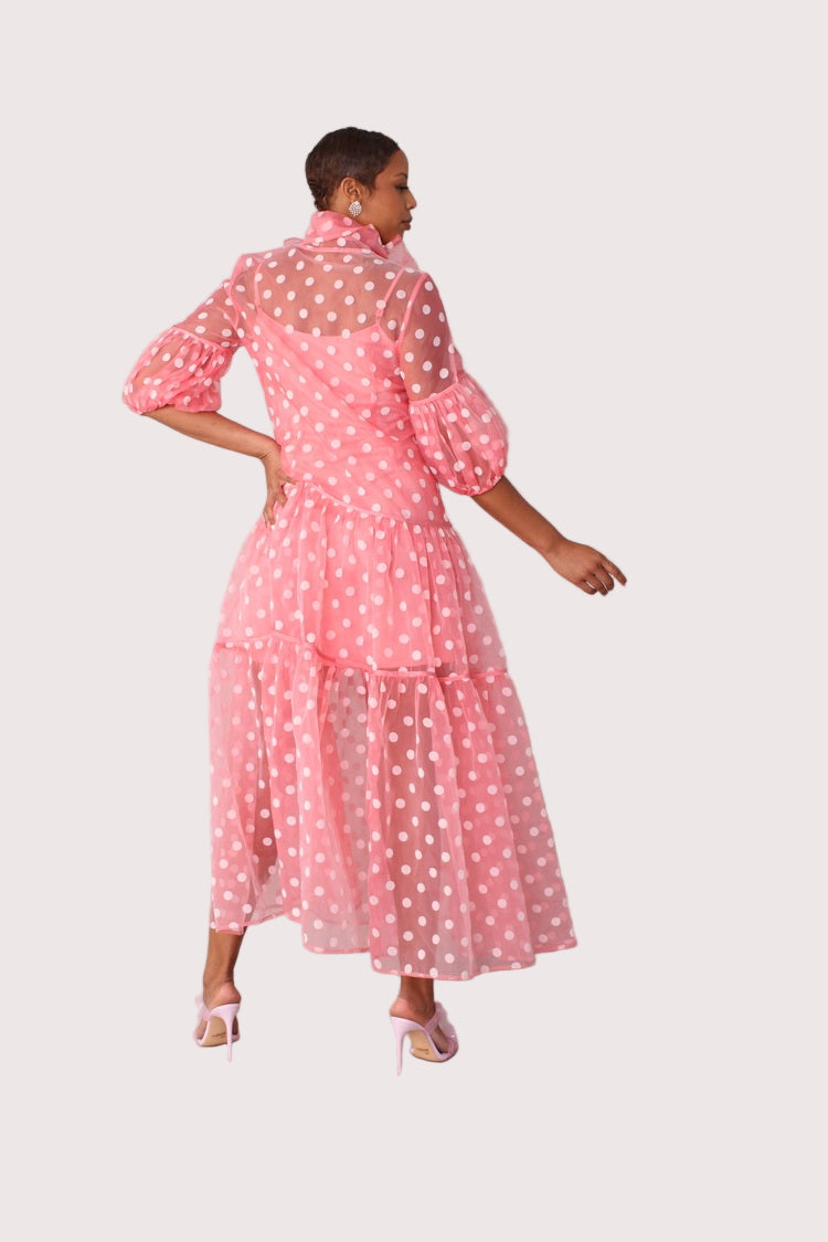 Polka dot organza maxi dress style 82234 in coral and white shown from the back in a standing pose highlighting the sheer polka dot fabric and tiered silhouette by For Her NYC