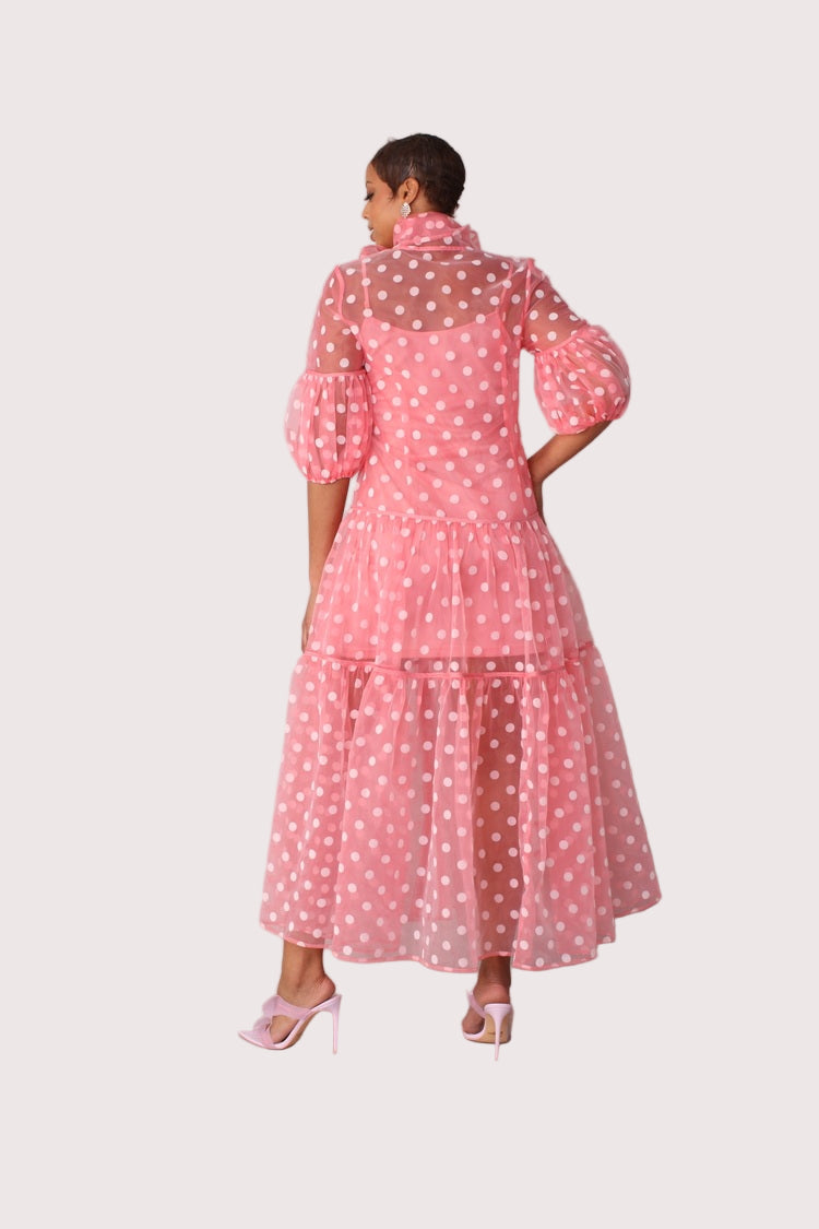 Polka dot organza maxi dress style 82234 in coral and white shown from the back in a standing pose highlighting the sheer polka dot fabric and tiered silhouette by For Her NYC