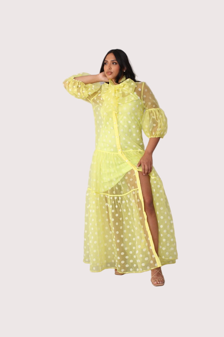 Polka dot organza maxi dress style 82234 in yellow and white shown with arm movement highlighting sleeve volume and lightweight drape by For Her NYC