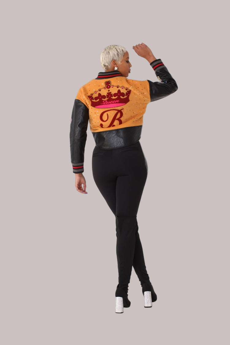 Betty Boop varsity crop jacket style 82236 in orange and black shown from the back in a standing pose highlighting the graphic back design and cropped fit by For Her NYC