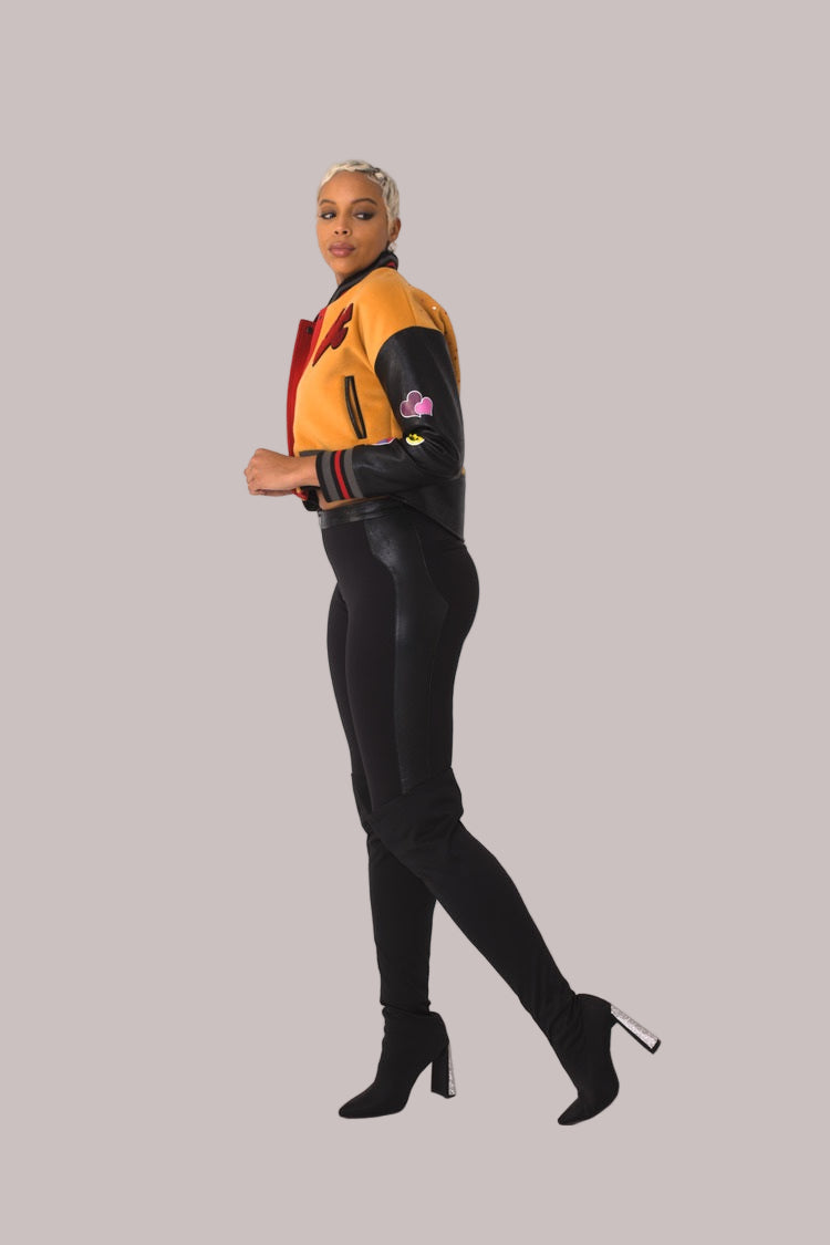 Betty Boop varsity crop jacket style 82236 in orange and black shown in a three-quarter standing pose highlighting varsity details and character patches by For Her NYC