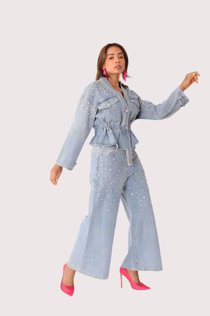 Pearl Cascade peplum denim jacket style 82325 in denim shown in a front walking pose showcasing movement, pearl accents, and the flattering peplum silhouette by For Her NYC