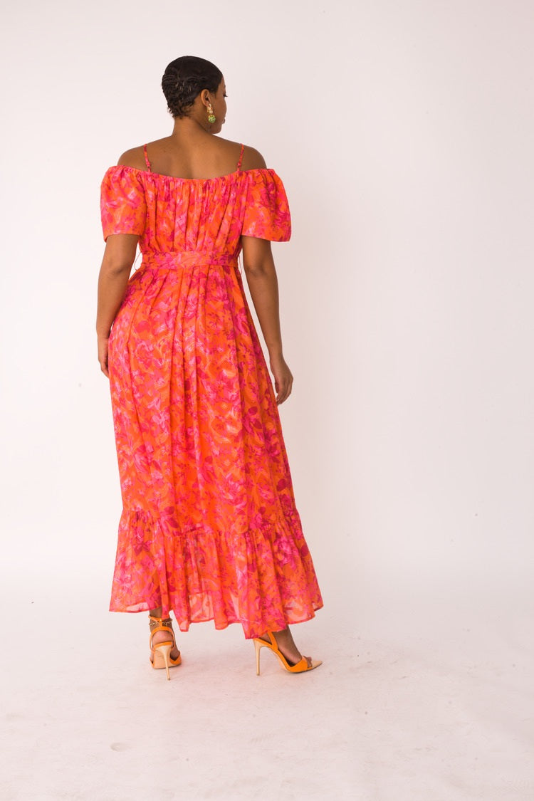 Sunset Bloom maxi dress style 82376 in multi print shown from the back in a standing pose highlighting the off-shoulder design and full-length drape by For Her NYC