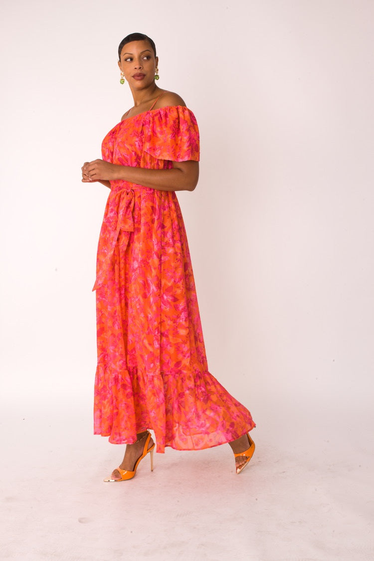 Sunset Bloom maxi dress style 82376 in vibrant multi print shown from the front in a standing pose highlighting the off-shoulder neckline and flowing silhouette by For Her NYC