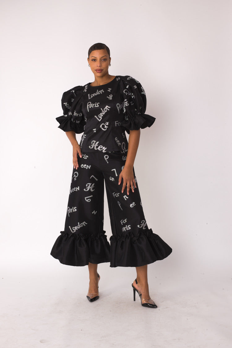 City Lights ruffle set style 82383 in black and silver shown front-facing in a standing pose highlighting the metallic city text print and dramatic ruffle details by For Her NYC