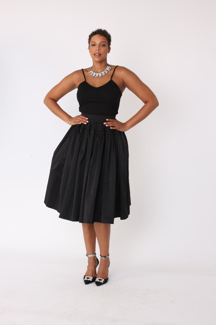 Black full circle taffeta skirt with hands-on-hips pose, structured waist detail visible, For Her NYC