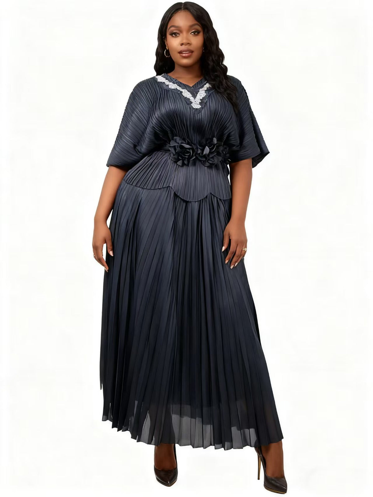 Model wearing a black pleated floral waist midi dress with flowing skirt and floral waist detail, front pose, For Her NYC