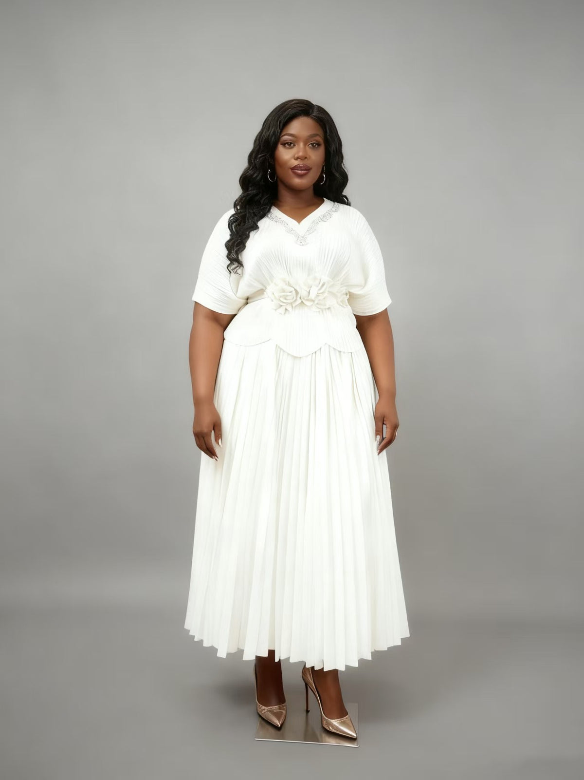 Model wearing a white pleated floral waist midi dress with flowing pleated silhouette and floral waist detail, front pose, For Her NYC