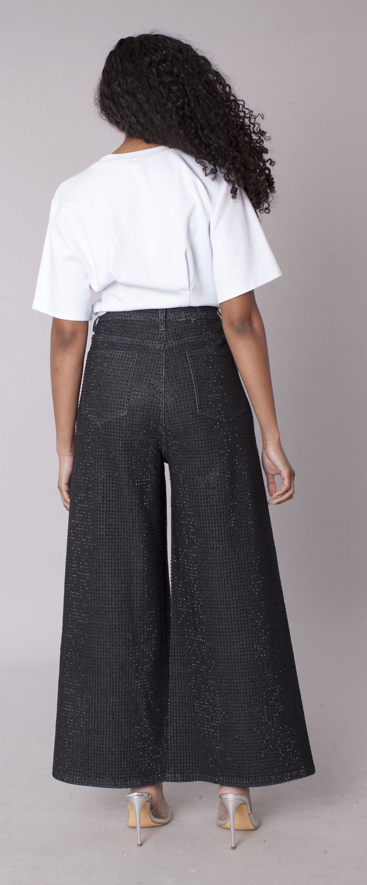 Black wide-leg trousers featuring subtle sparkle detailing and flowing wide-leg fit, model showing back view styled with white top For Her NYC