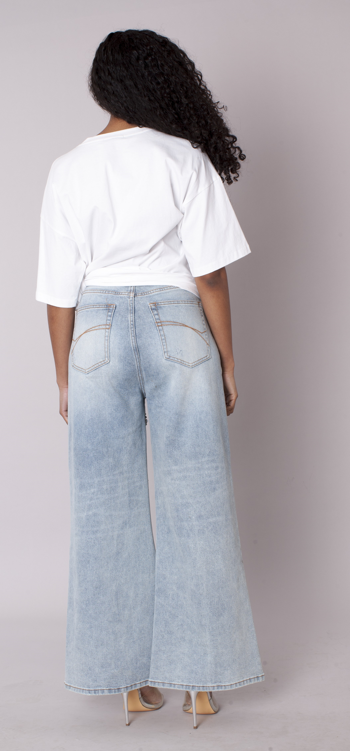 Light wash wide-leg denim jeans featuring starburst pearl embellishments, model showing back view styled with white top For Her NYC