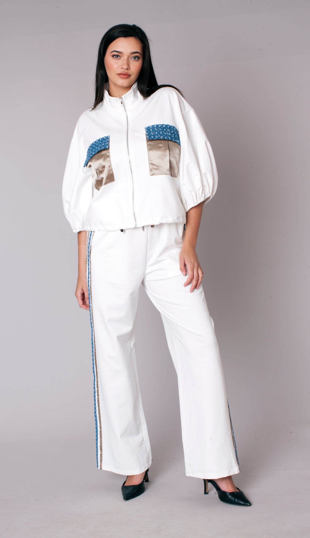 Woman wearing a white embellished track pant set with zip-front jacket, puff sleeves, satin pocket accents, and wide leg pants – For Her NYC