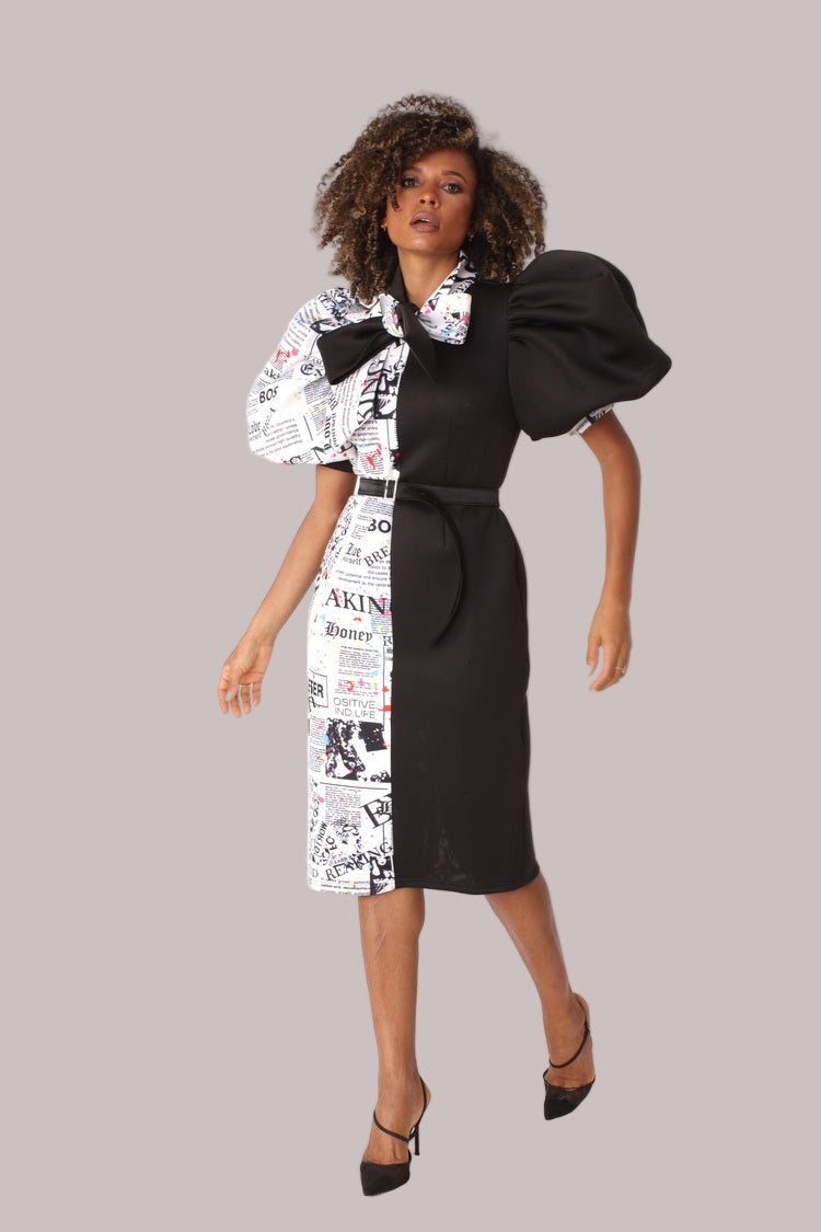 Model wearing black print puff sleeve midi dress with bow tie collar, front walking pose showcasing movement and eye-catching print by For Her NYC