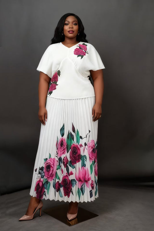 Front view of model wearing a white pleated skirt set with floral print and flowing midi skirt, For Her NYC