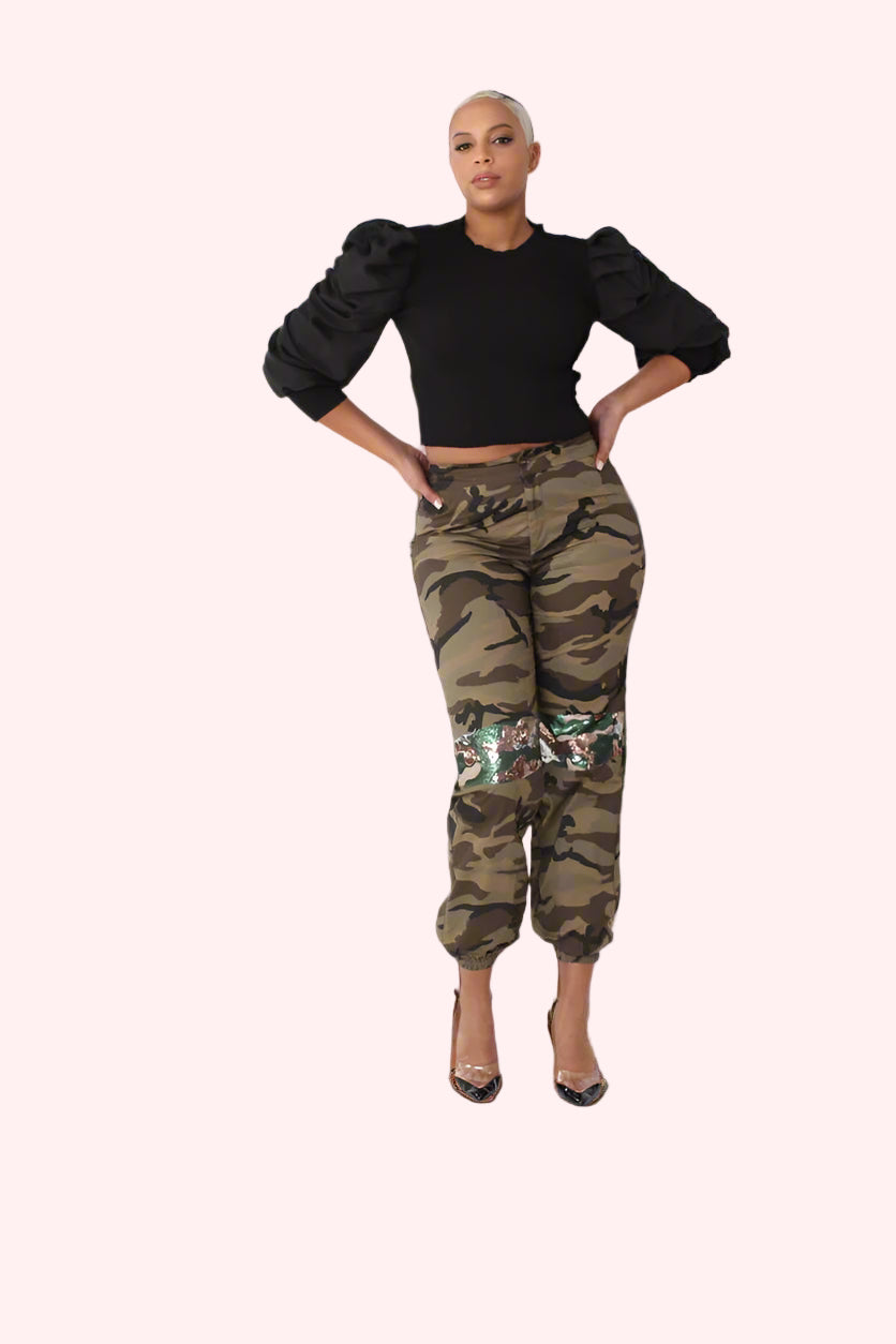 Front pose with hands on hips showcasing camo sequin joggers with relaxed fit and fashion-forward detailing by For Her NYC