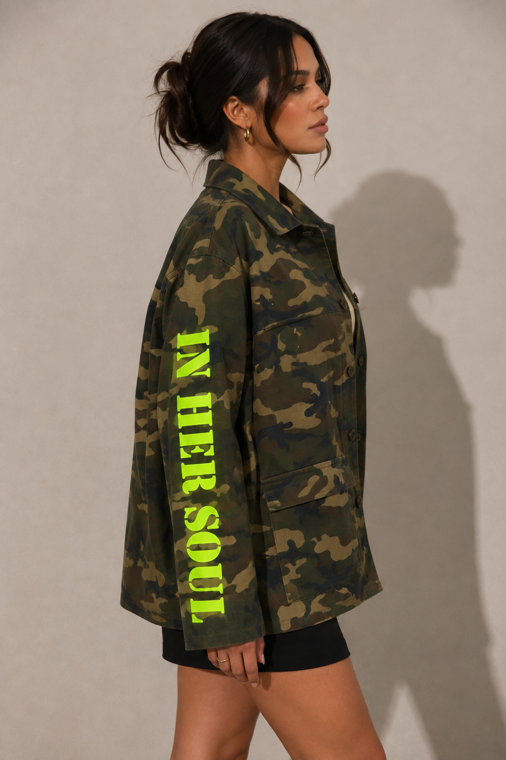 Model wearing camouflage utility jacket, side-facing hero pose highlighting oversized fit, graphic camo print, and utility pocket details by For Her NYC
