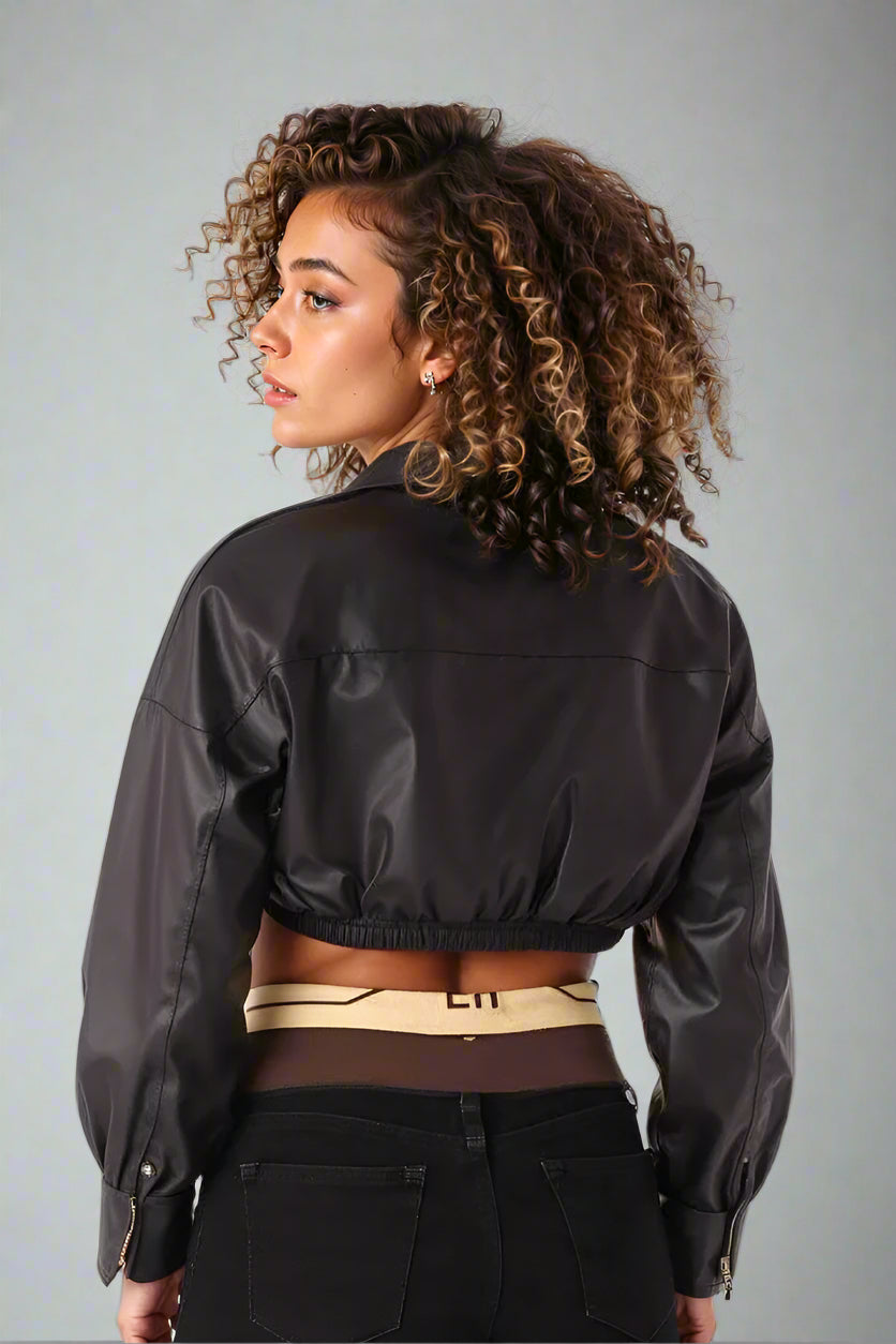 Back view of black cropped faux leather wrap top showing cinched hem and sleek glossy finish.