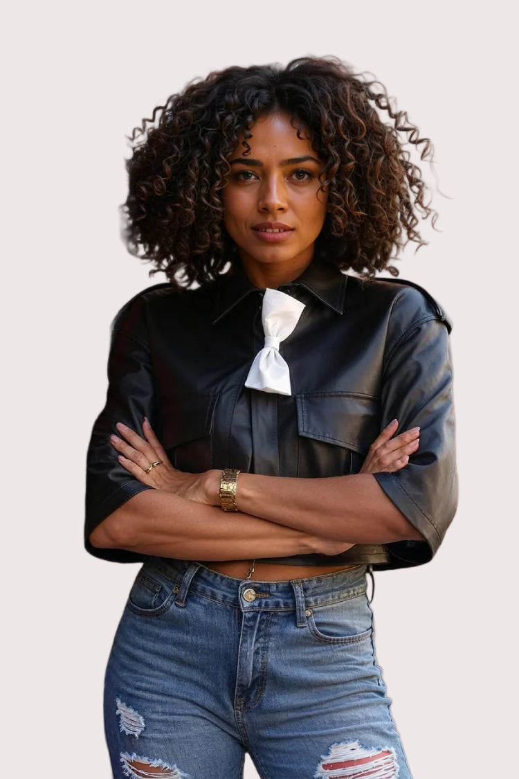 Crossed arms: Black cropped leather jacket with white bow accent, arms crossed front pose, For Her NYC.