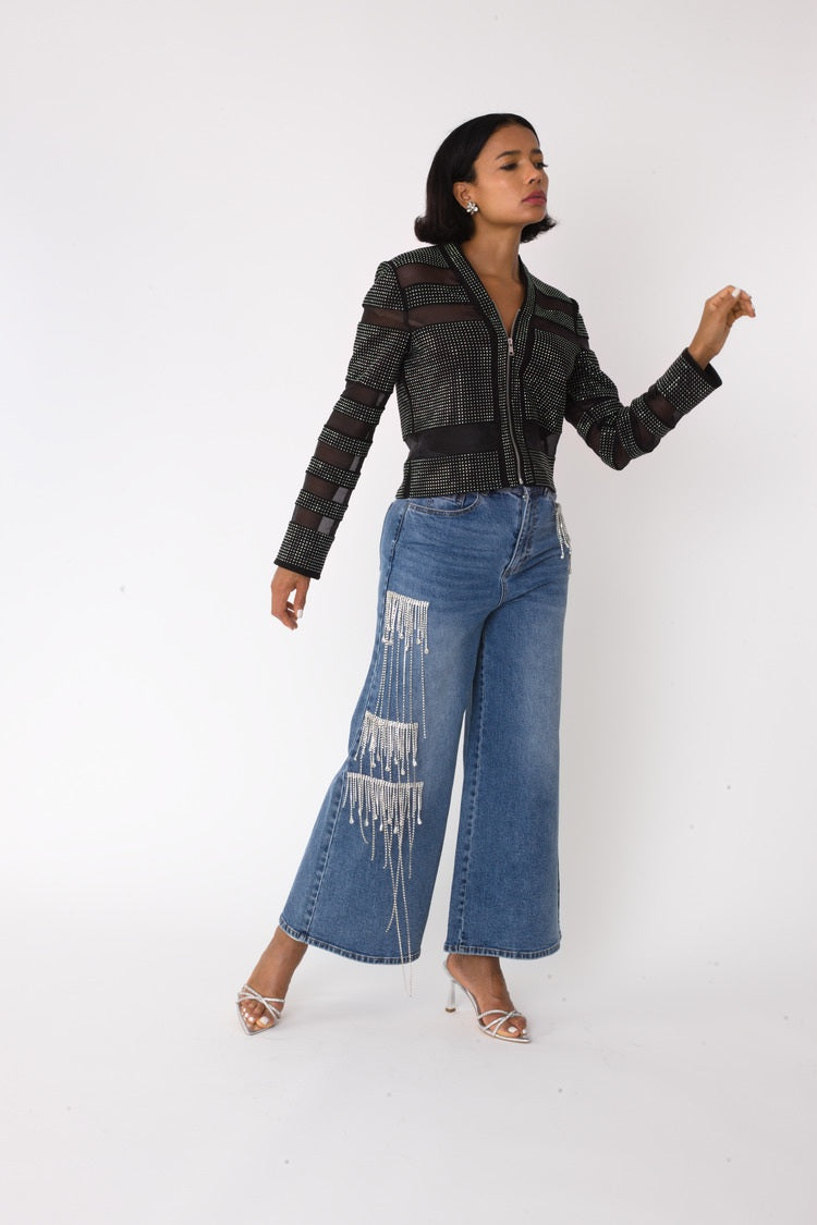 Model wearing the denim crystal cascade wide leg jeans with arm raised in a dynamic pose, showcasing movement and cascading crystal embellishments by For Her NYC