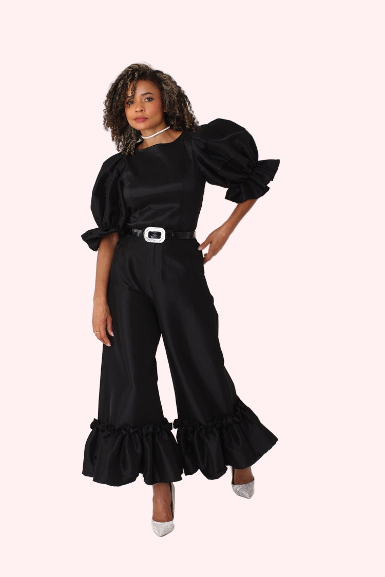 Model wearing black dramatic ruffle hem wide leg pants standing front-facing with elegant wide leg fit by For Her NYC