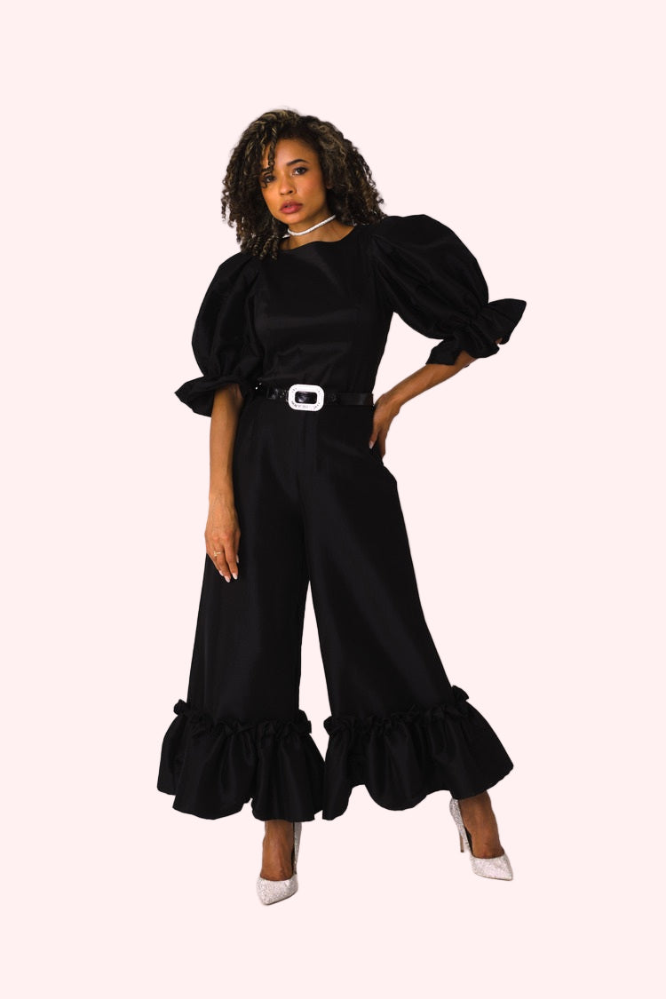Model wearing black dramatic ruffle hem wide leg pants standing front-facing with elegant wide leg fit by For Her NYC