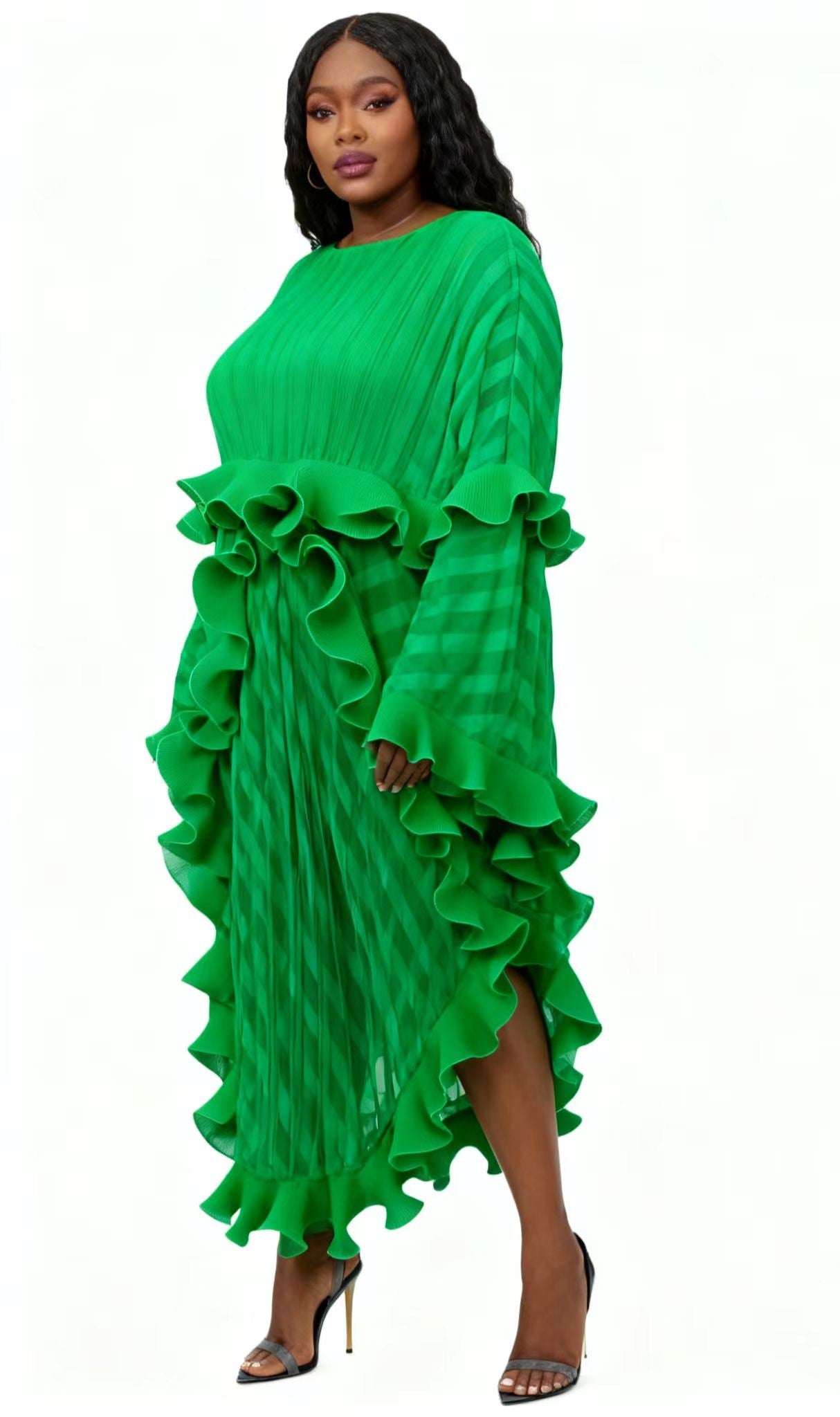 Model wearing a green pleated maxi dress with dramatic cascading ruffles and flowing silhouette – For Her NYC