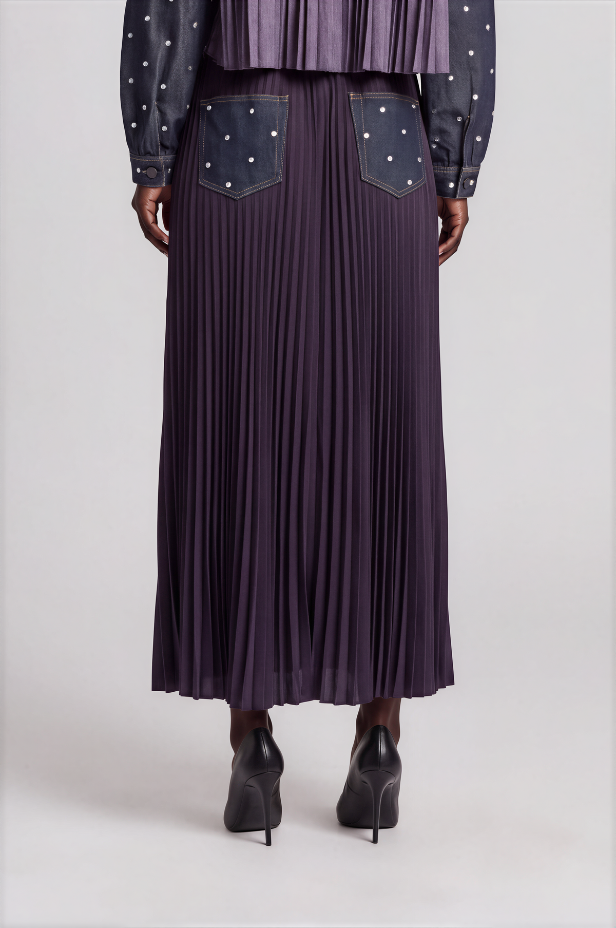 Back detail of a model wearing the dark-wash For Her NYC Embellished Denim Maxi Skirt - 82963 with pleated panels and embellished denim pockets