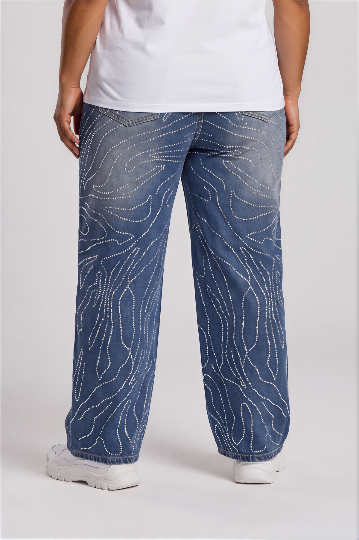 Back view of a plus-size model wearing the For Her NYC Rhinestone Swirl Wide-Leg Denim Jeans - 83071 with back pockets and allover rhinestone detailing
