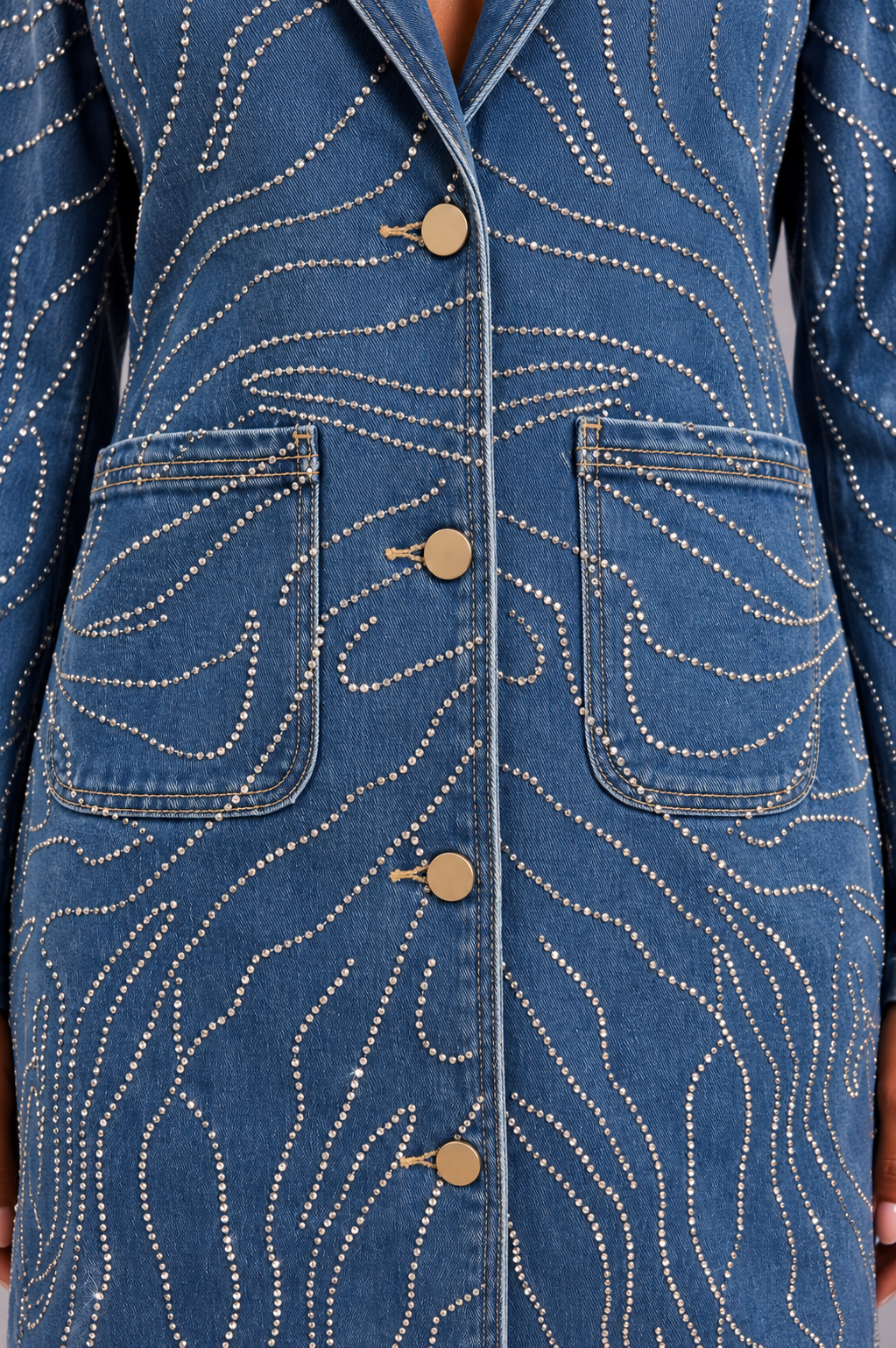 Close front view of a model wearing the medium-wash For Her NYC Rhinestone Swirl Denim Duster Coat - 83070 with lapels, buttons and patch pockets