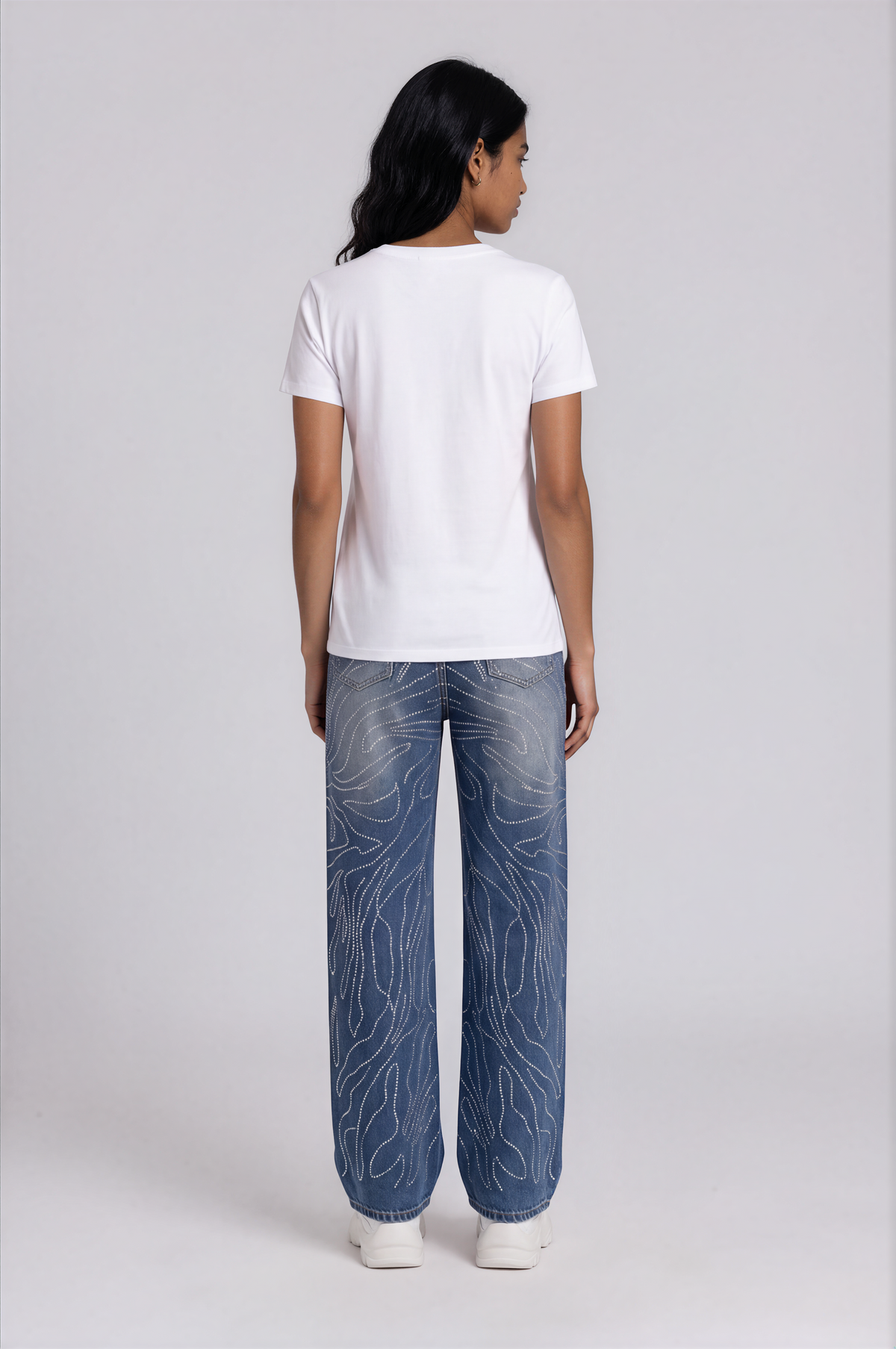 Back view of a model wearing the For Her NYC Rhinestone Swirl Wide-Leg Denim Jeans - 83071 with back pockets and allover rhinestone swirl detailing