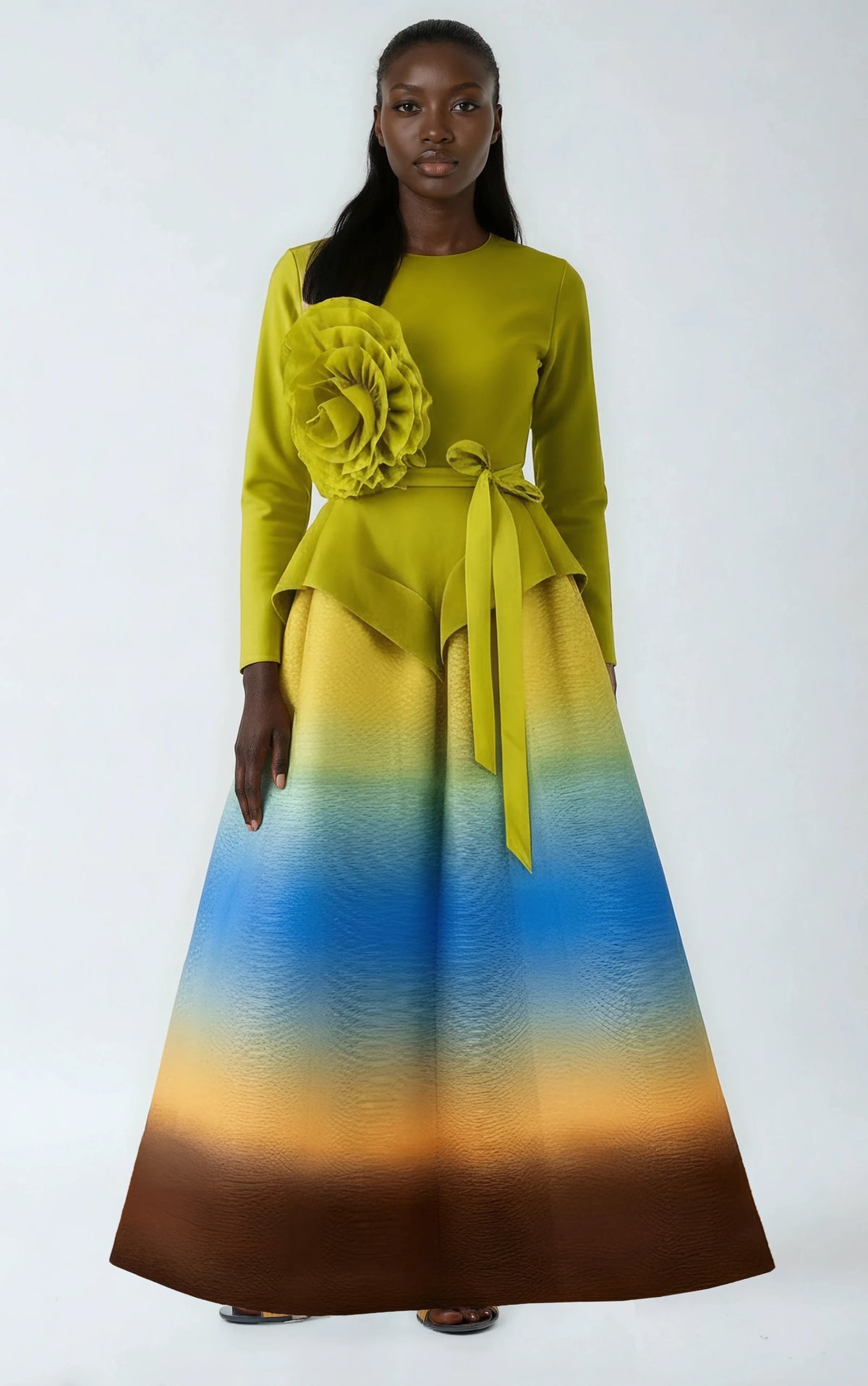 Model wearing multi-color ombre pleated skirt set with floral accent and long-sleeve top by For Her NYC.