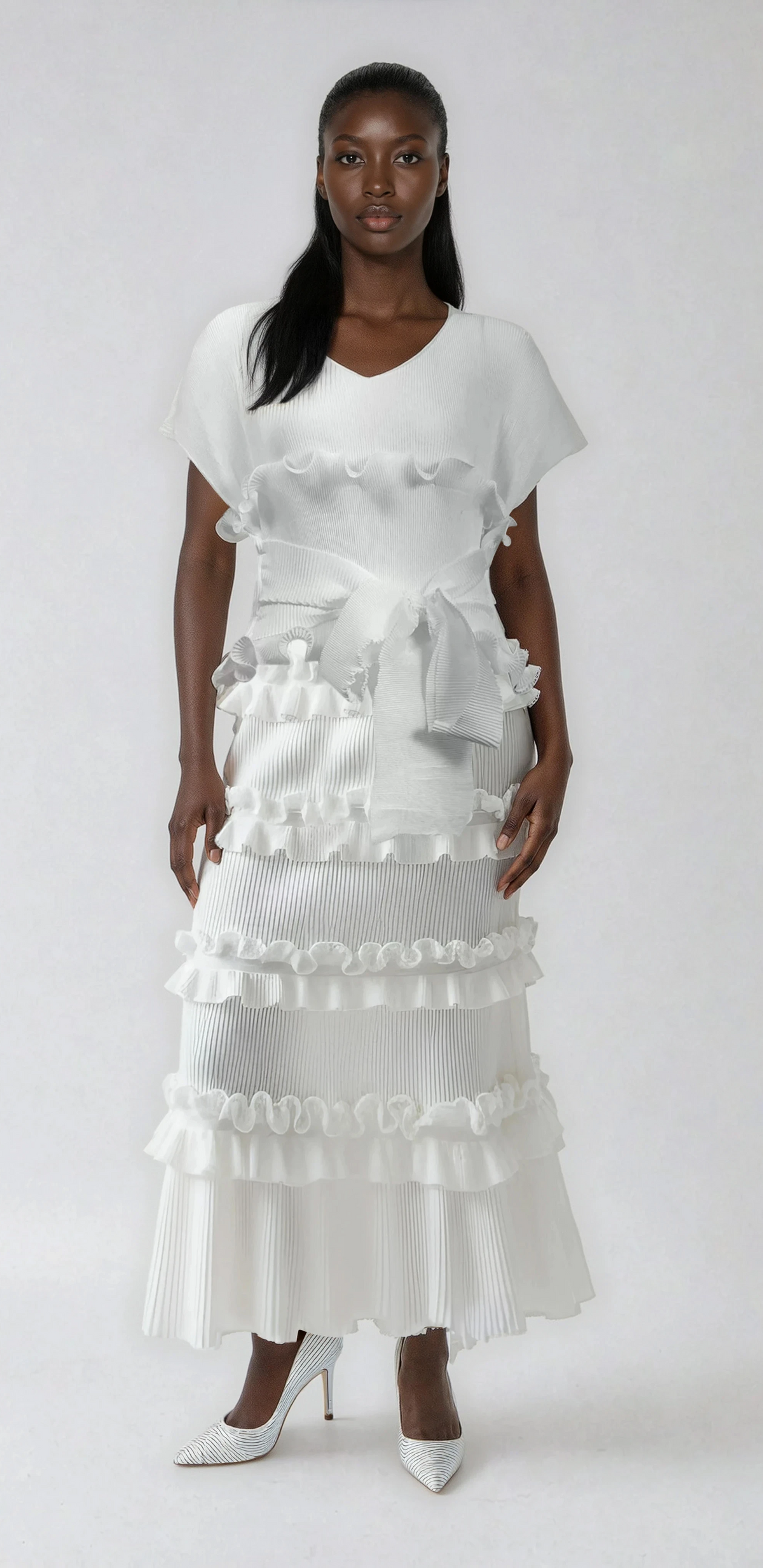 Model wearing white ruffled pleated maxi dress with defined waist tie and sculptural pleats by For Her NYC.