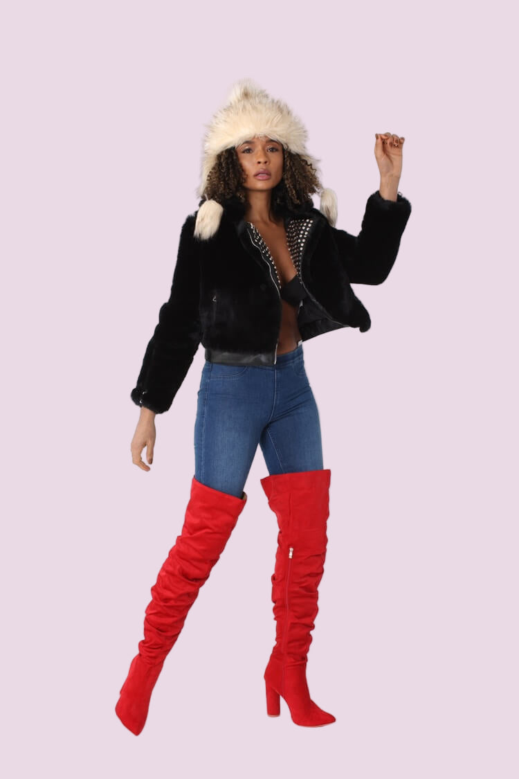 Model wearing a black faux fur jacket with a studded lapel shown in a front angled pose, highlighting the cropped silhouette, textured faux fur, and edgy stud detailing, styled with denim and statement boots by For Her NYC