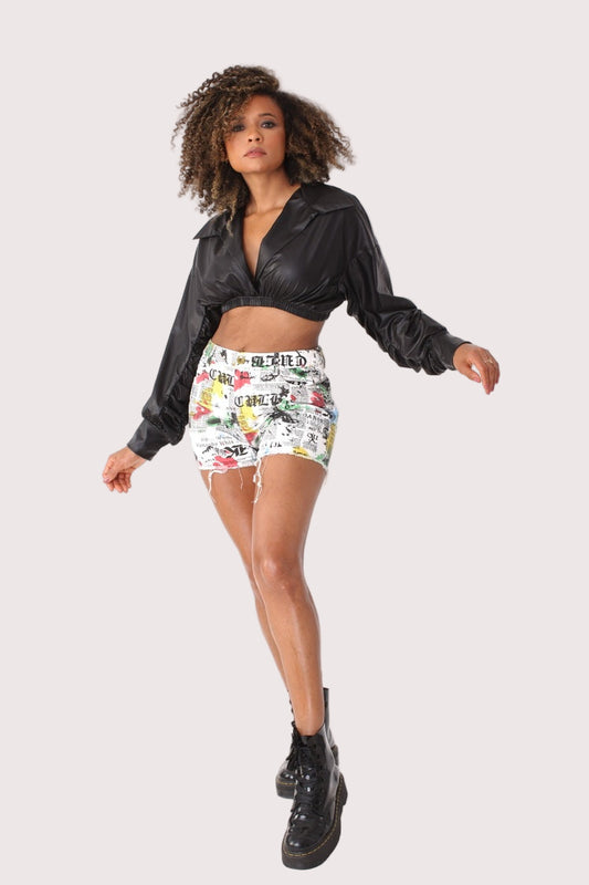 Model wearing white multi graffiti-print distressed denim shorts in a front walking pose, highlighting high-waisted fit and frayed hem, For Her NYC