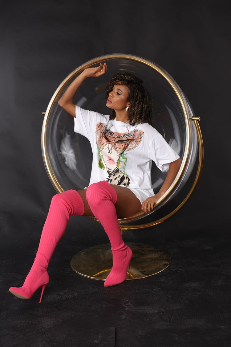 Seated studio view of graphic print t-shirt with stud embellishments highlighting oversized silhouette and edgy streetwear styling by For Her NYC