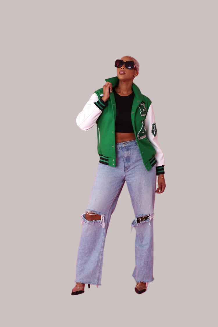 Angled front view of green varsity jacket worn open with white sleeves and patches – For Her NYC